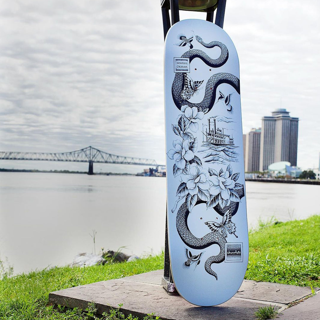 A skateboard chillin next to a lake with a bridge in the background