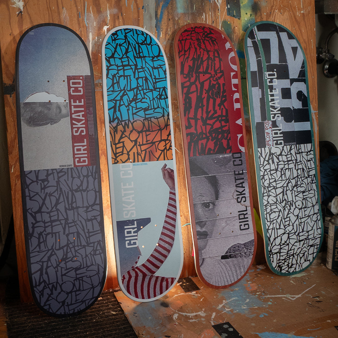 Four skateboard decks with various designs and branding on a wooden surface.