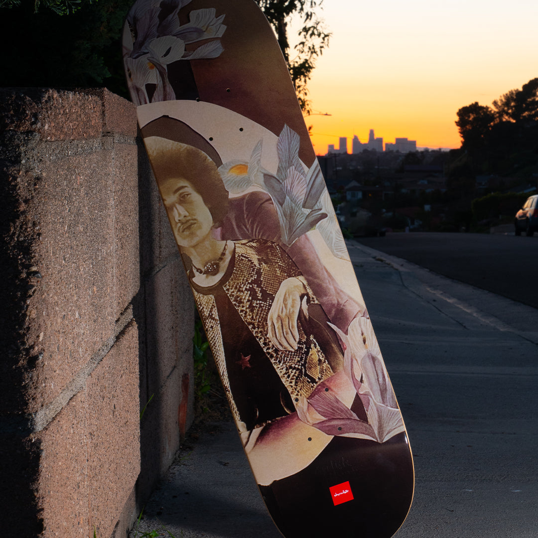A skateboard on a sidewalk sitting up against a brick wall