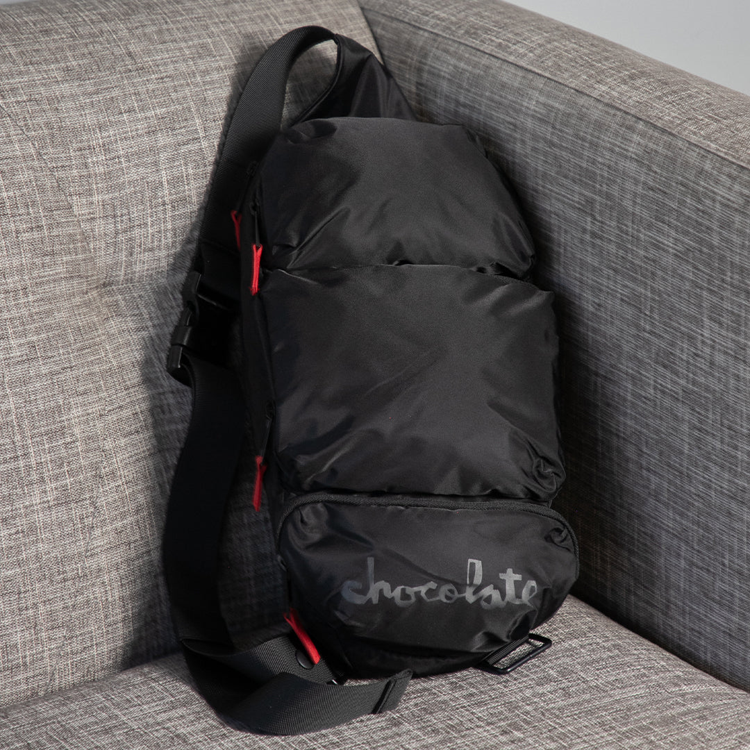 Black backpack with 'chocolate' branding on a gray couch